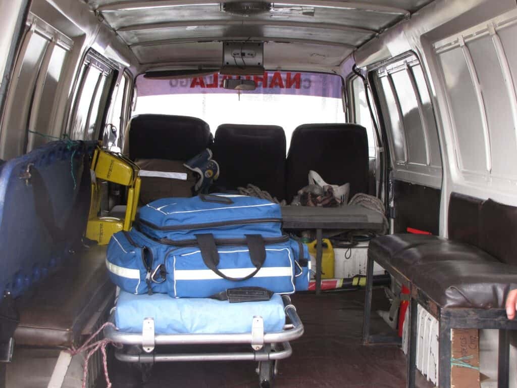 An old Ferno stretcher lashed in place with rope. The floor locks to hold it are no longer made.