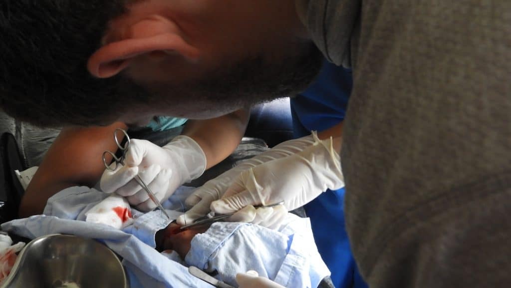 AMEDICAusa volunteer Efim Oykhman repairs a machete wound, Hospital Nacional Retalhuleu